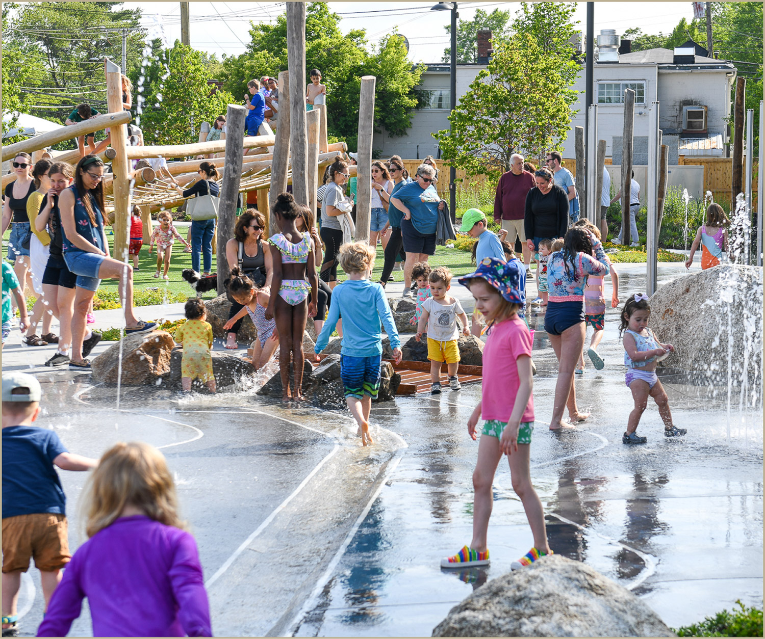 Families and children enjoying a splash park and playground at the Pattern District in Newton Upper Falls, MA.