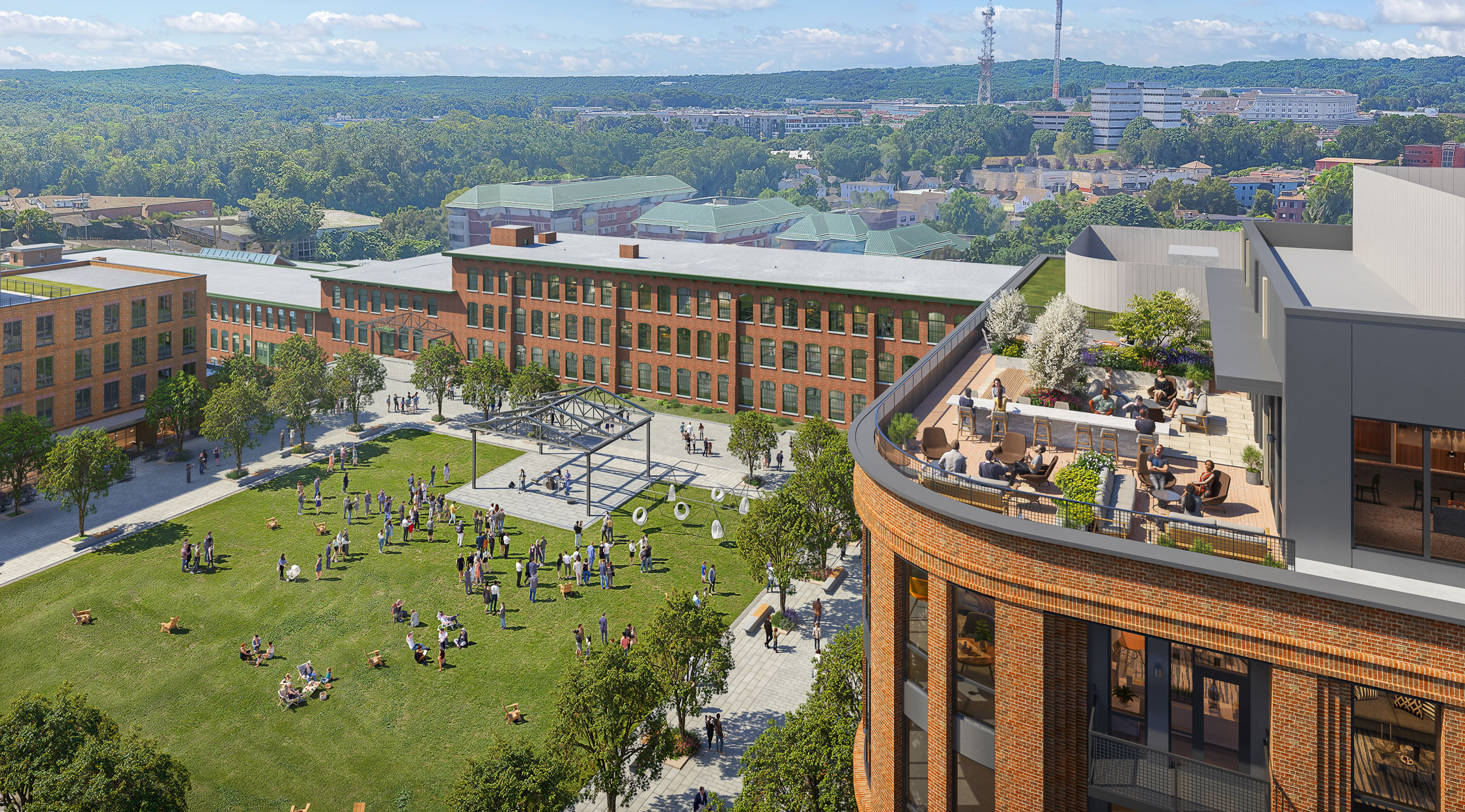 Aerial of the Pattern District in Newton Upper Falls, MA, featuring a Village Green space, restored brick mill buildings, and rooftop gathering areas.